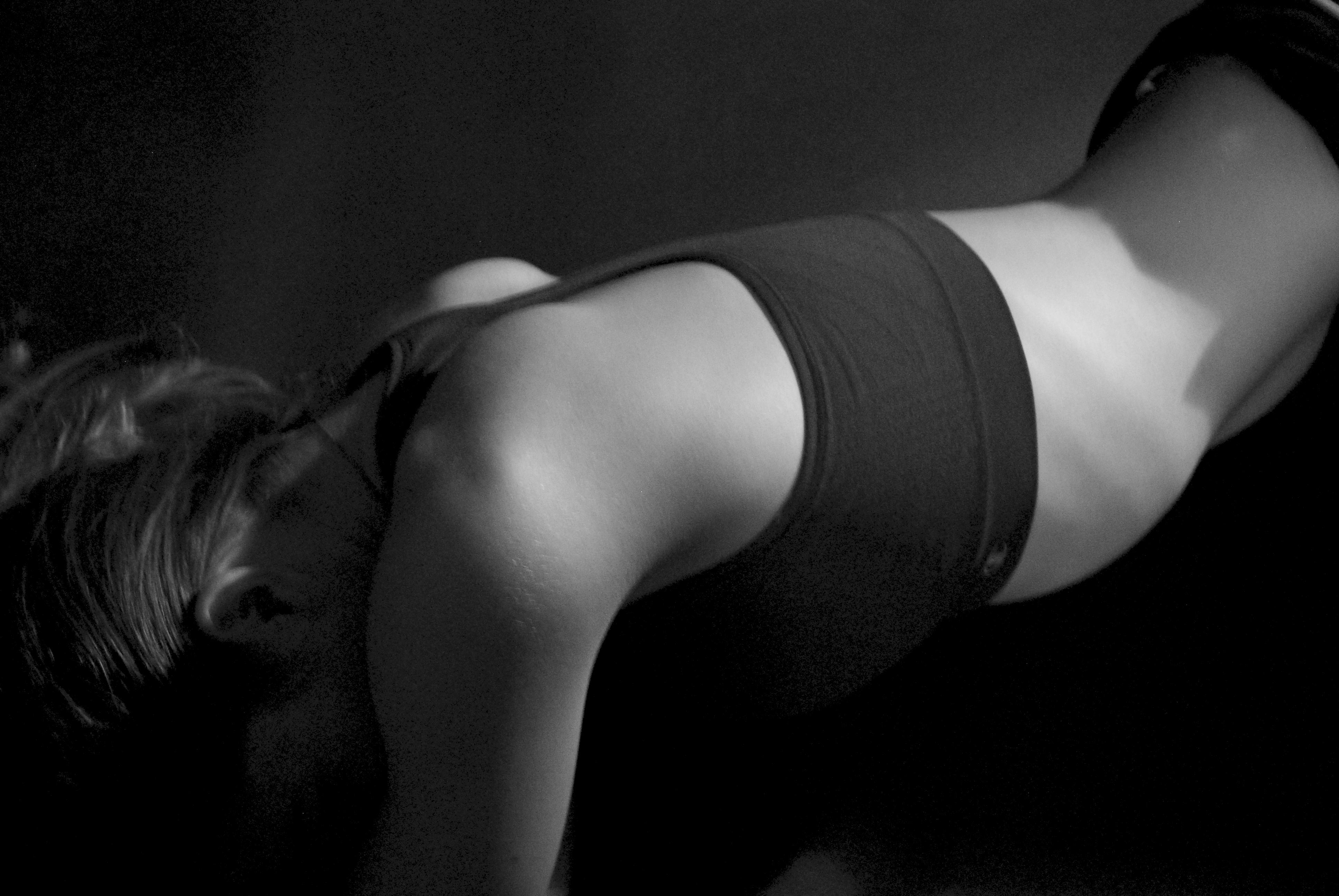 Black and white photo of a woman's torso and side profile on a black background