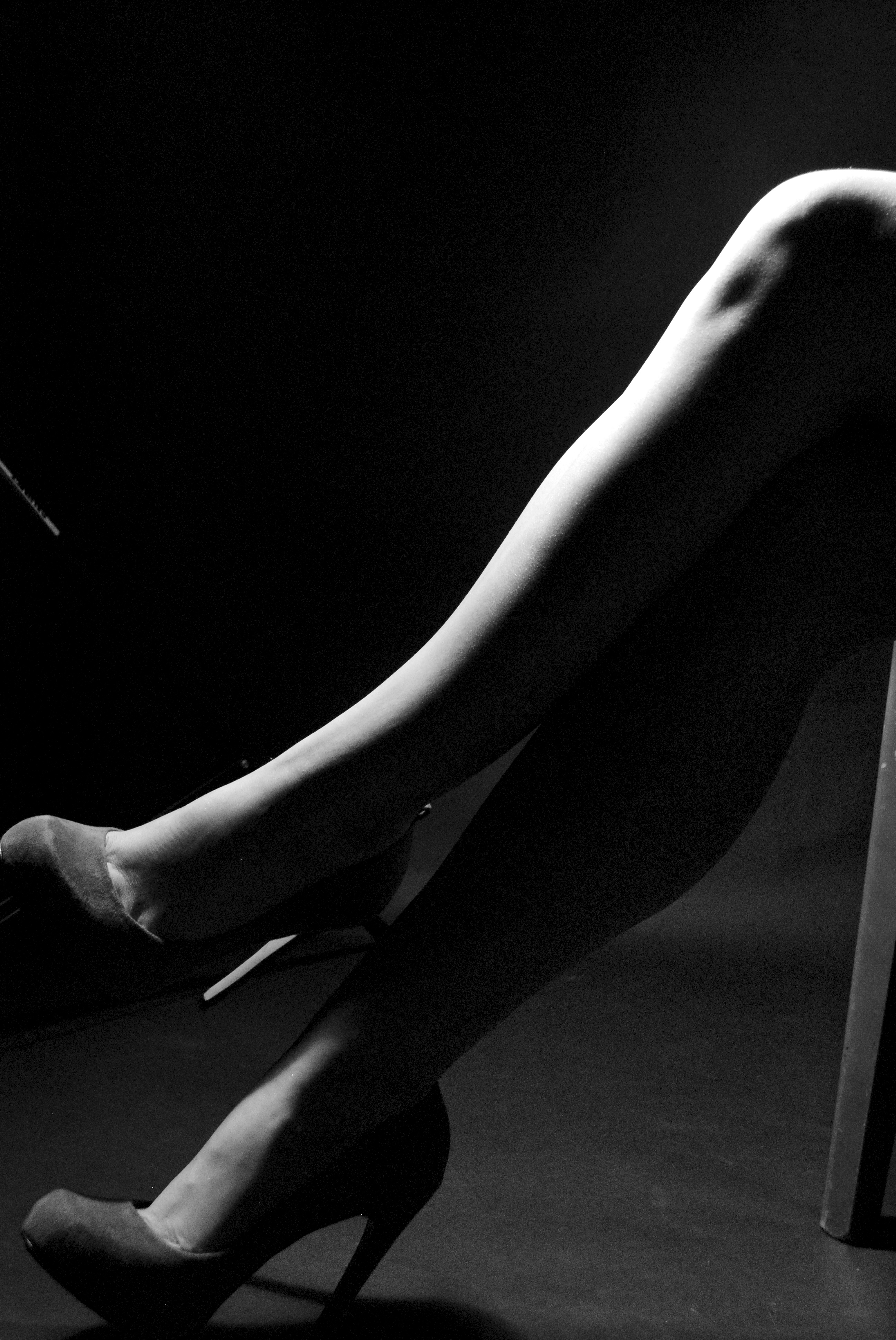 Black and white photo of a high contrast pair of crossed legs in heels